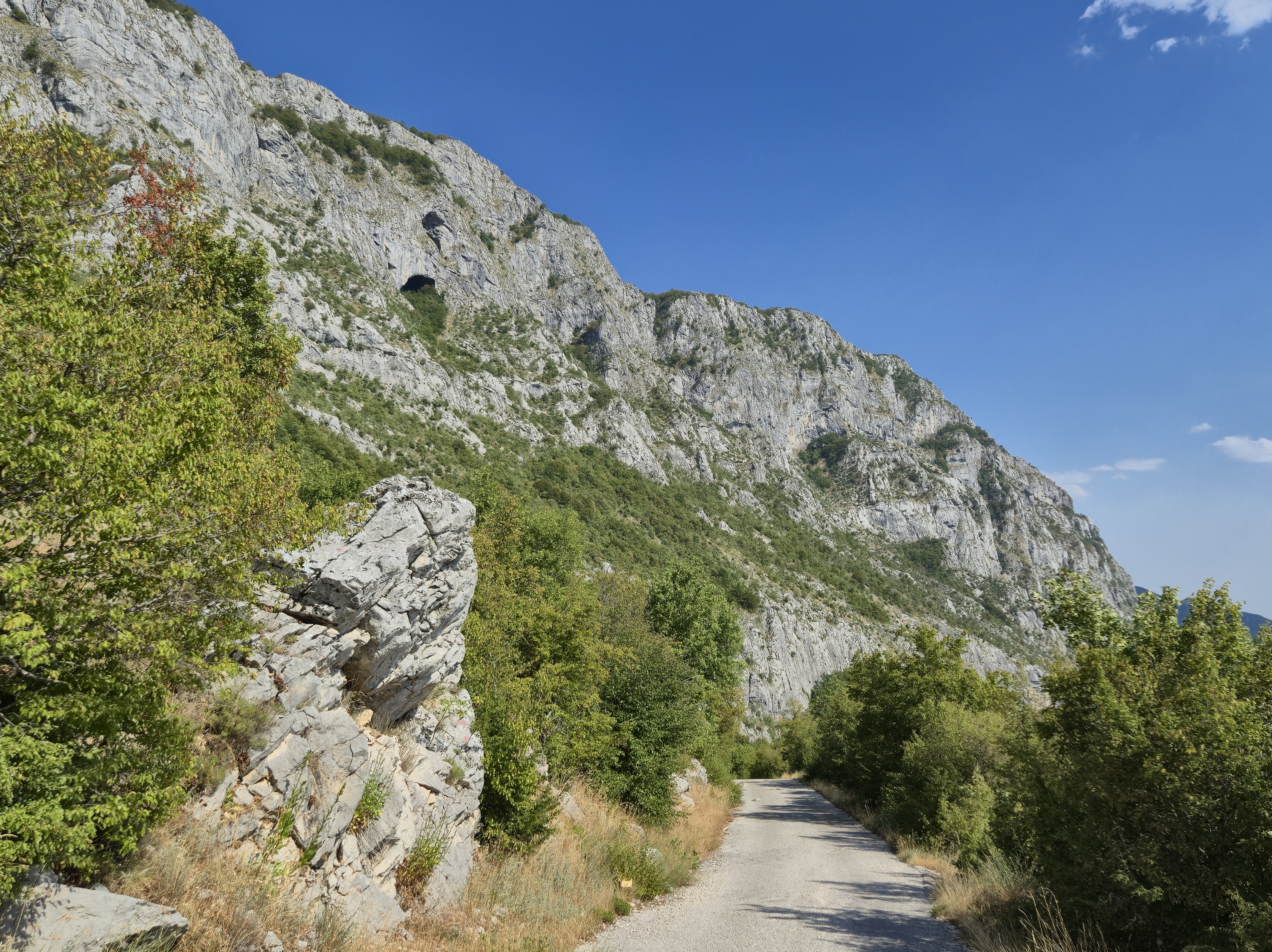 Small road leading next to a rock wall